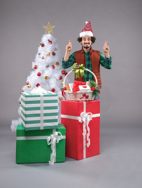 Vue de face jeune homme autour de cadeaux de vacances à la lumière