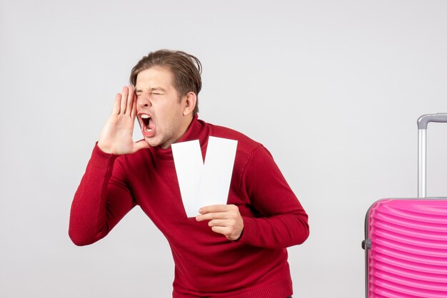 Vue de face jeune homme avec des billets d'avion sur fond blanc