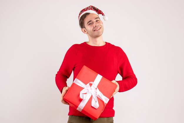 Vue de face jeune homme avec bonnet de Noel debout sur fond blanc espace libre