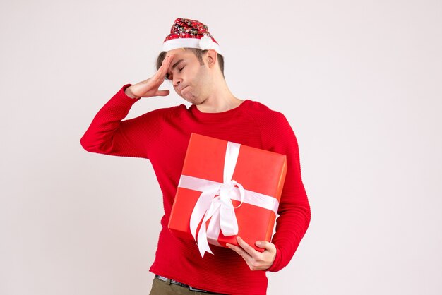 Vue de face jeune homme avec bonnet de Noel debout sur fond blanc espace libre