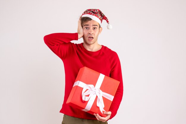 Vue de face jeune homme avec bonnet de Noel tenant sa tête sur fond blanc