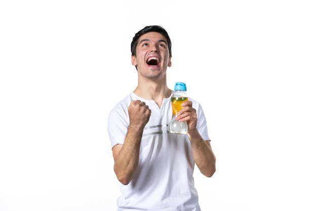 Vue de face jeune homme avec une bouteille de limonade sur une surface blanche