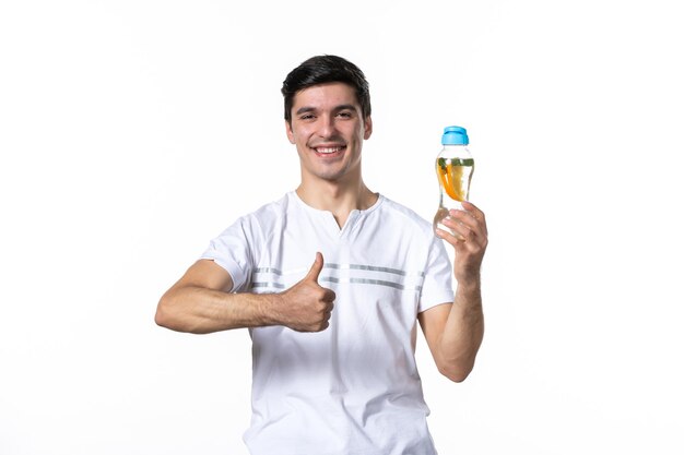 Vue de face jeune homme avec une bouteille de limonade sur une surface blanche