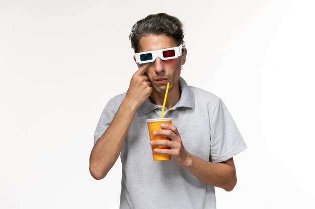 Vue de face jeune homme buvant du soda et portant des lunettes de soleil sur un bureau blanc