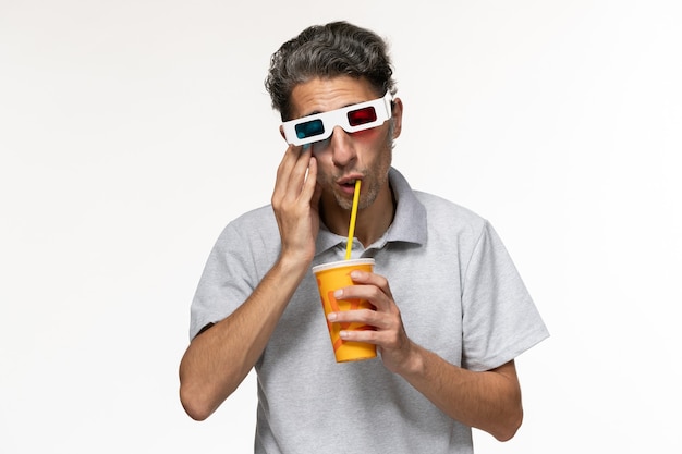 Vue de face jeune homme buvant du soda et portant des lunettes de soleil sur une surface blanc clair