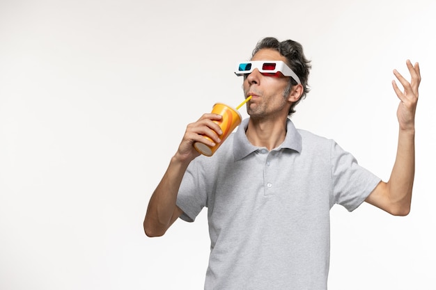 Vue de face jeune homme buvant du soda et portant des lunettes de soleil sur une surface blanche