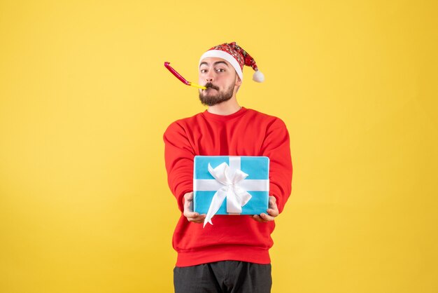 Vue de face jeune homme avec cadeau de Noël sur jaune