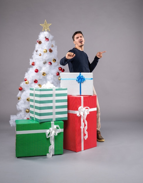 Vue de face jeune homme avec des cadeaux de Noël à la lumière