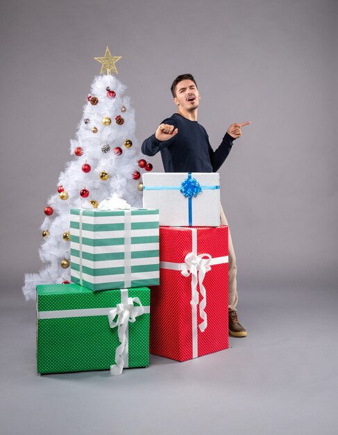 Vue de face jeune homme avec des cadeaux de Noël à la lumière