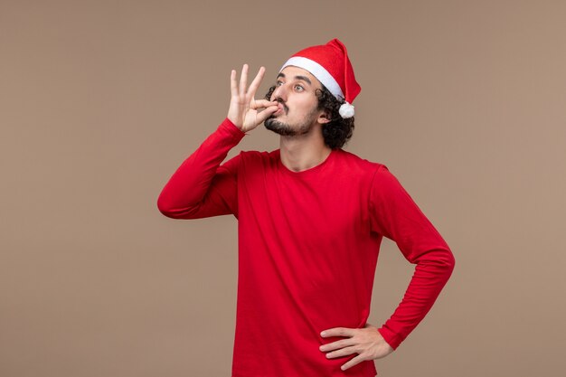 Vue de face jeune homme avec cape de Noël sur le fond marron vacances d'émotion de Noël