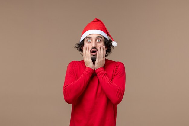 Vue de face jeune homme avec cape de Noël sur le fond marron vacances d'émotion de Noël