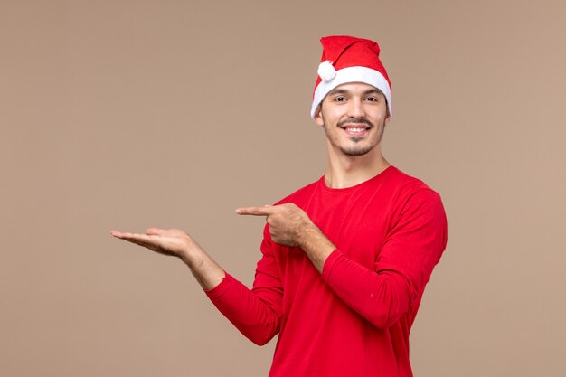 Vue de face jeune homme avec cape de Noël rouge sur espace brun