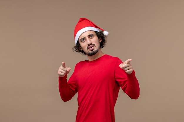 Vue de face jeune homme avec cape de Noël rouge sur fond marron vacances d'émotion de Noël