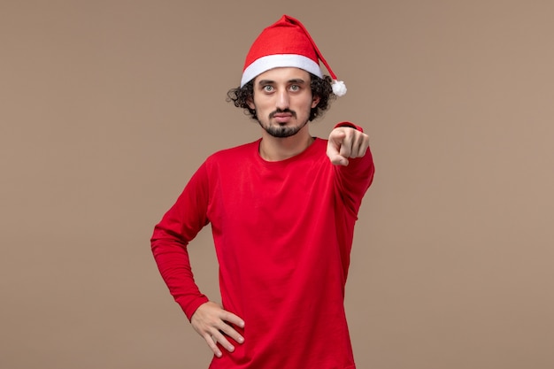 Vue de face jeune homme avec cape de Noël rouge sur fond marron vacances émotions Noël