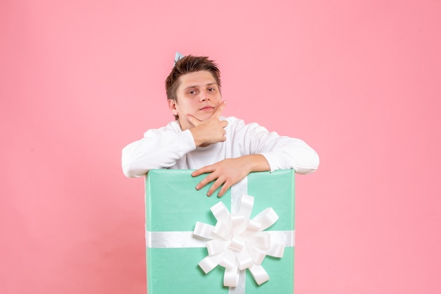 Photo gratuite vue de face jeune homme en chemise blanche avec capuchon et présent sur le fond rose