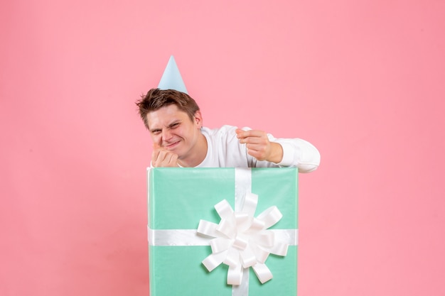 Vue de face jeune homme en chemise blanche avec capuchon et présent sur le fond rose