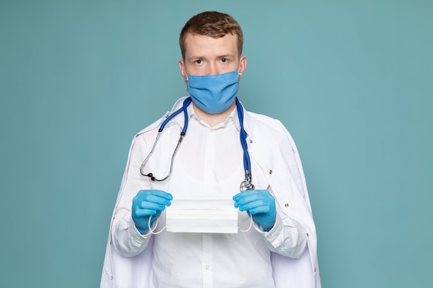 Une vue de face jeune homme en chemise blanche et gants bleus avec masque bleu sur l'espace bleu