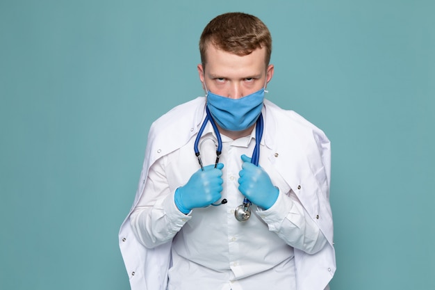 Une vue de face jeune homme en chemise blanche et gants bleus avec masque sur l'espace bleu