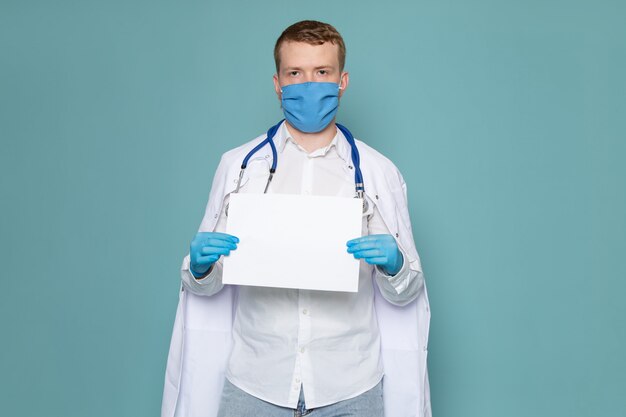 Une vue de face jeune homme en chemise blanche et gants bleus tenant un morceau de papier sur l'espace bleu