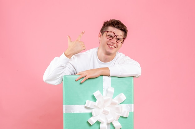 Vue de face jeune homme en chemise blanche avec présent sur le fond rose