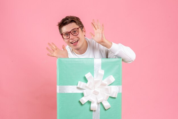 Vue de face jeune homme en chemise blanche avec présent sur le fond rose