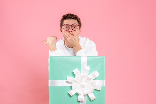 Photo gratuite vue de face jeune homme en chemise blanche avec présent surpris sur fond rose