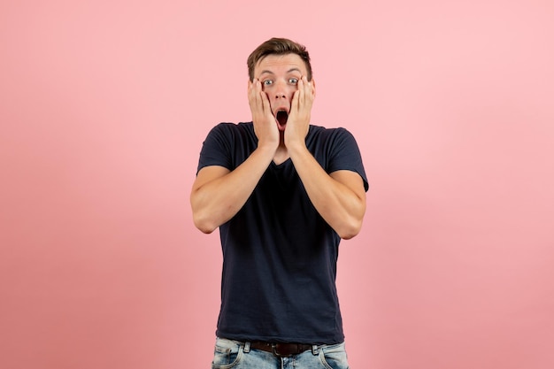 Vue De Face Jeune Homme En Chemise Bleu Foncé Posant Avec Une Expression Choquée Sur Fond Rose