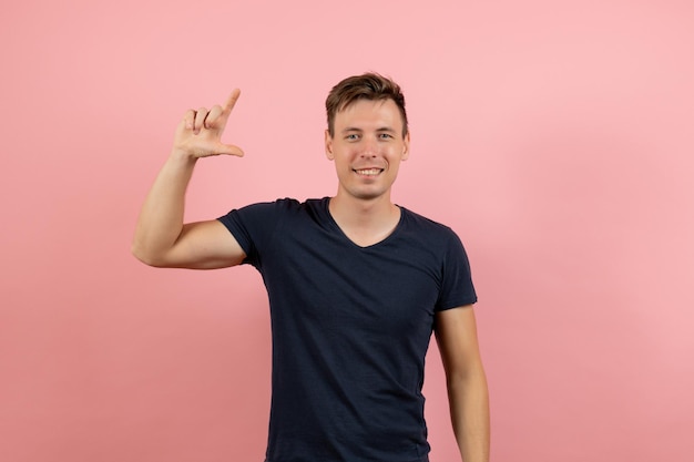 Vue de face jeune homme en chemise bleu foncé posant avec le sourire sur fond rose