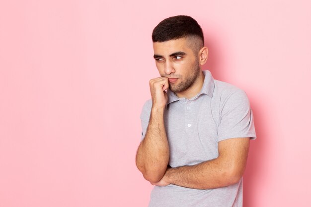 Vue de face jeune homme en chemise grise pensant profondément sur rose