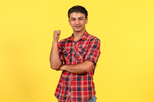 Vue de face jeune homme en chemise lumineuse posant sur le modèle masculin de couleur de bureau jaune