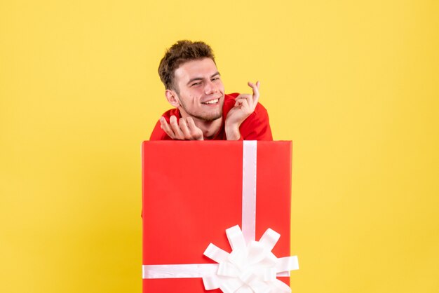 Vue De Face Jeune Homme En Chemise Rouge Assis à L'intérieur De La Boîte Actuelle