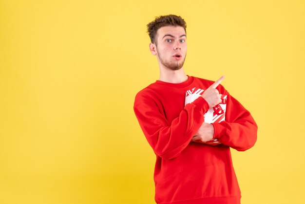 Vue de face jeune homme en chemise rouge avec cadeau de Noël