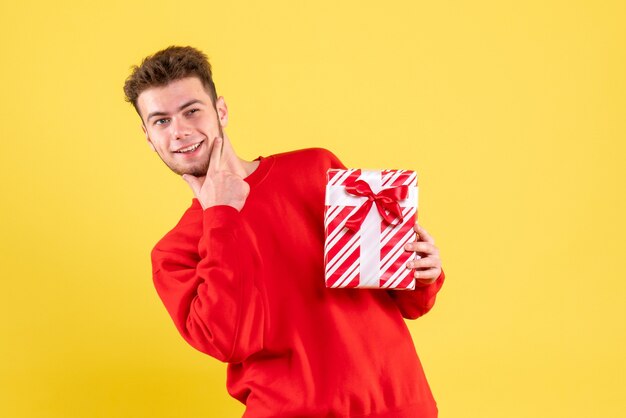 Vue de face jeune homme en chemise rouge avec cadeau de Noël