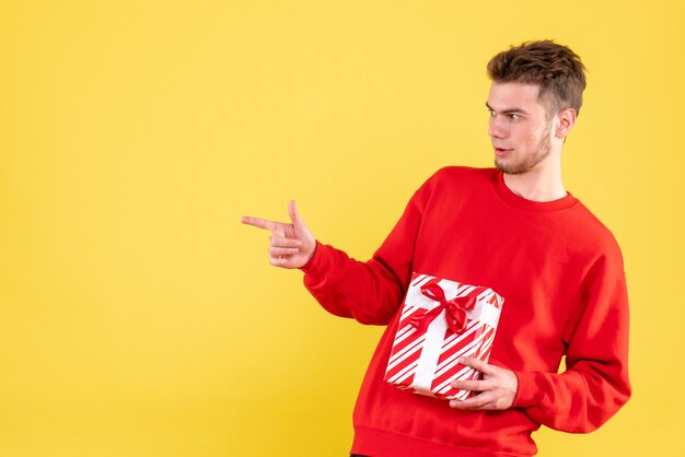 Vue de face jeune homme en chemise rouge avec cadeau de Noël