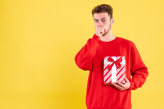 Vue de face jeune homme en chemise rouge avec cadeau de Noël