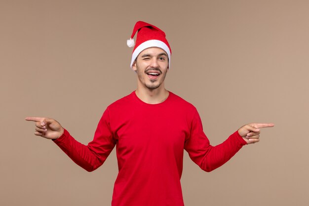 Vue de face jeune homme clignant sur fond marron émotion vacances noël