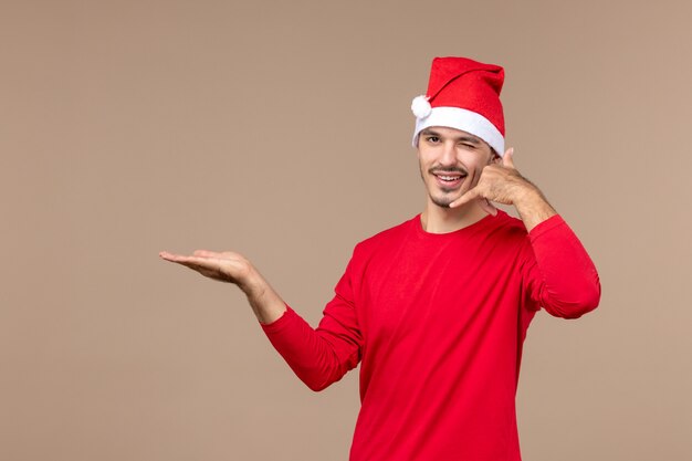 Vue de face jeune homme avec un clin d'oeil expression sur fond marron mâle vacances couleur émotion