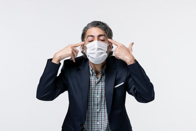 Vue De Face D'un Jeune Homme Concentré En Costume Portant Un Masque Et Réfléchissant Profondément Sur Une Surface Blanche