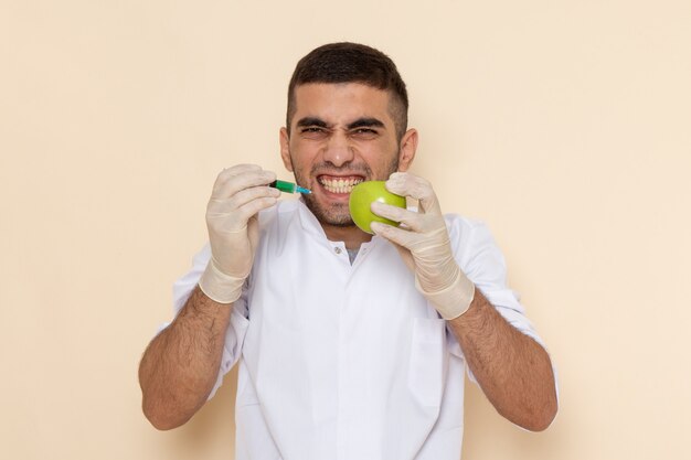 Vue de face jeune homme en costume blanc portant des gants d'injection de pomme sur beige