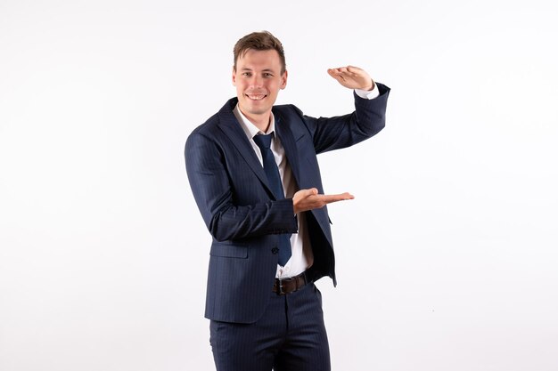 Vue de face jeune homme en costume classique élégant montrant la taille avec ses mains sur fond blanc