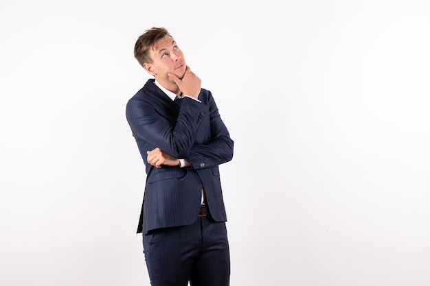 Vue de face jeune homme en costume classique élégant pensant sur fond blanc