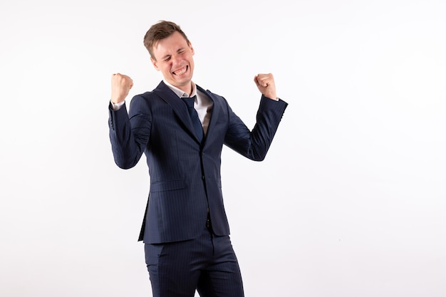 Vue de face jeune homme en costume classique élégant se réjouissant de joie sur fond blanc