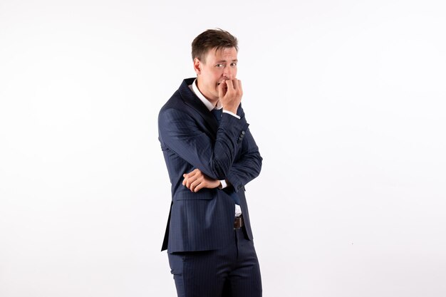 Vue de face jeune homme en costume classique élégant se sentant nerveux sur fond blanc