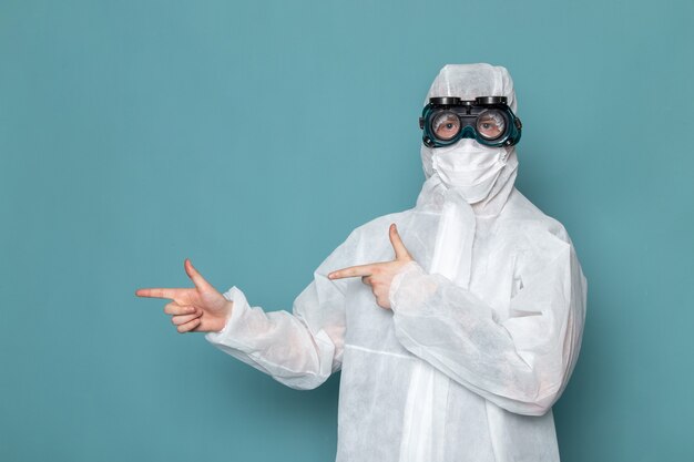 Une vue de face jeune homme en costume spécial blanc portant des lunettes de soleil spéciales sur le mur bleu homme costume couleur équipement spécial danger