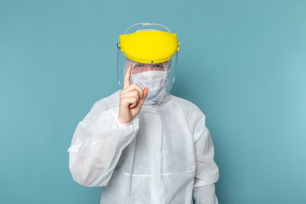 Une vue de face jeune homme en costume spécial blanc portant un masque spécial sur le mur bleu homme costume couleur équipement spécial danger