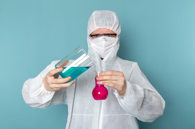 Photo gratuite une vue de face jeune homme en costume spécial blanc solutions de mélange sur le mur bleu homme costume couleur équipement spécial danger