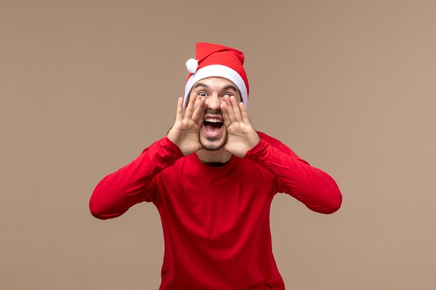 Vue de face jeune homme criant sur fond marron émotion vacances mâle