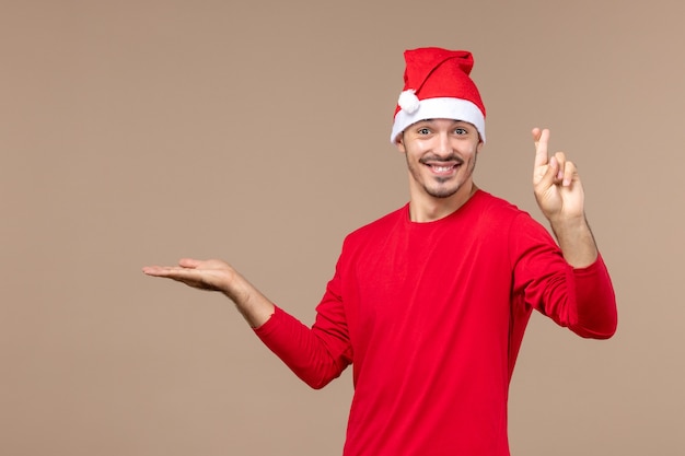 Vue de face jeune homme croisant ses doigts sur fond marron couleur masculine émotion vacances