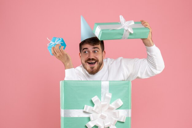 Vue de face jeune homme debout à l'intérieur de la boîte présente sur le pyjama de couleur rose party photo émotion sommeil Noël