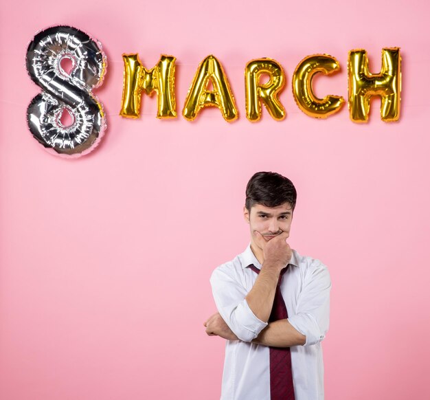 Vue de face jeune homme avec décoration de mars sur fond rose couleur présente égalité fête mariage femmes jour homme